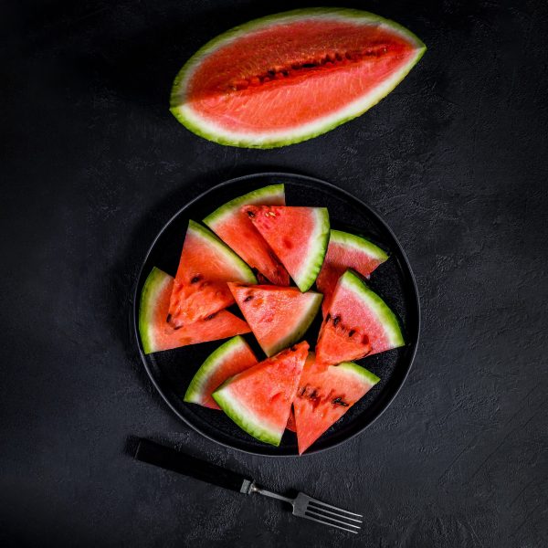 Slices of ripe watermelon in a plate on a dark background. Selective focus.