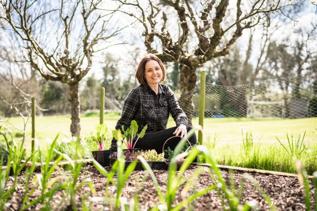 She Grows Veg Founder Kate sits alongside a vegetable patch in winter. 